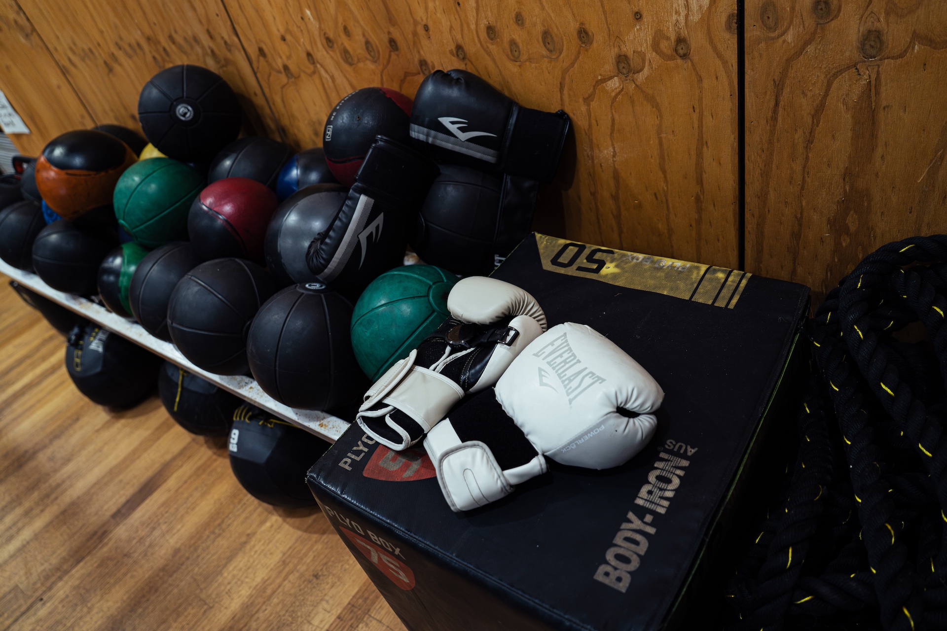 Medicine balls, gloves and battle ropes stacked by the wall