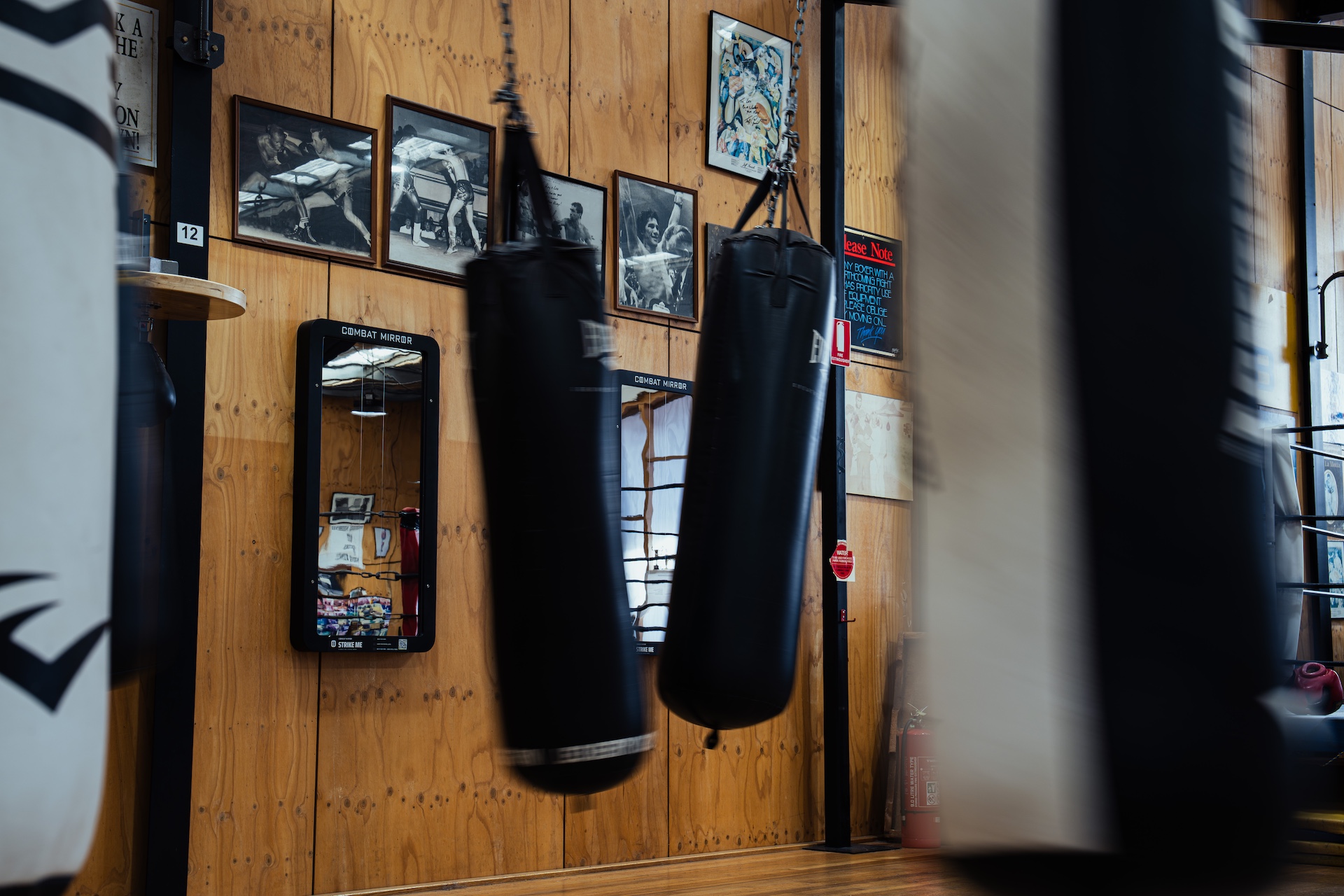 Heavy bags swinging past framed boxing photographs
