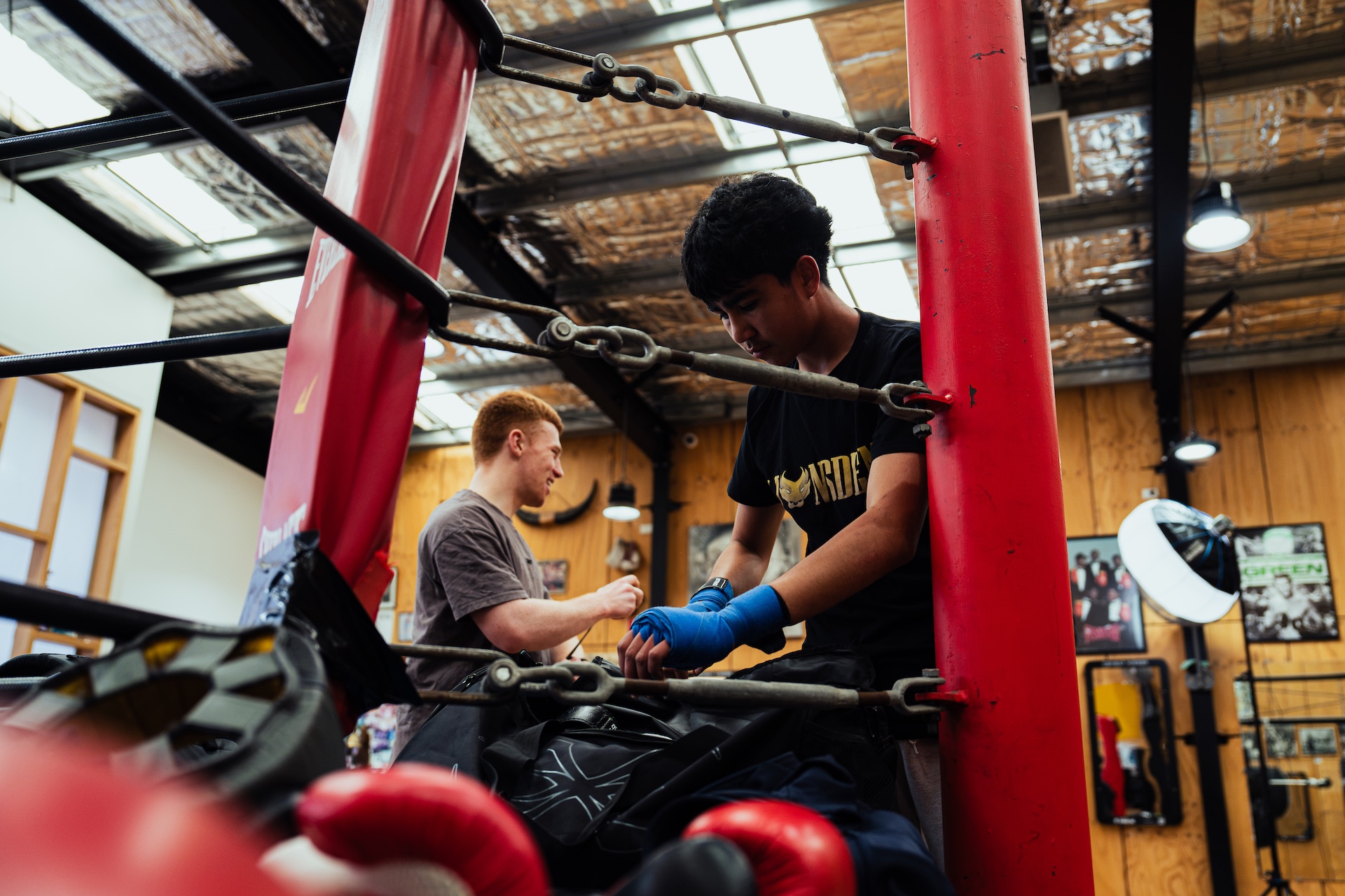 Coach helping a boxer wrap his hands beside the ring