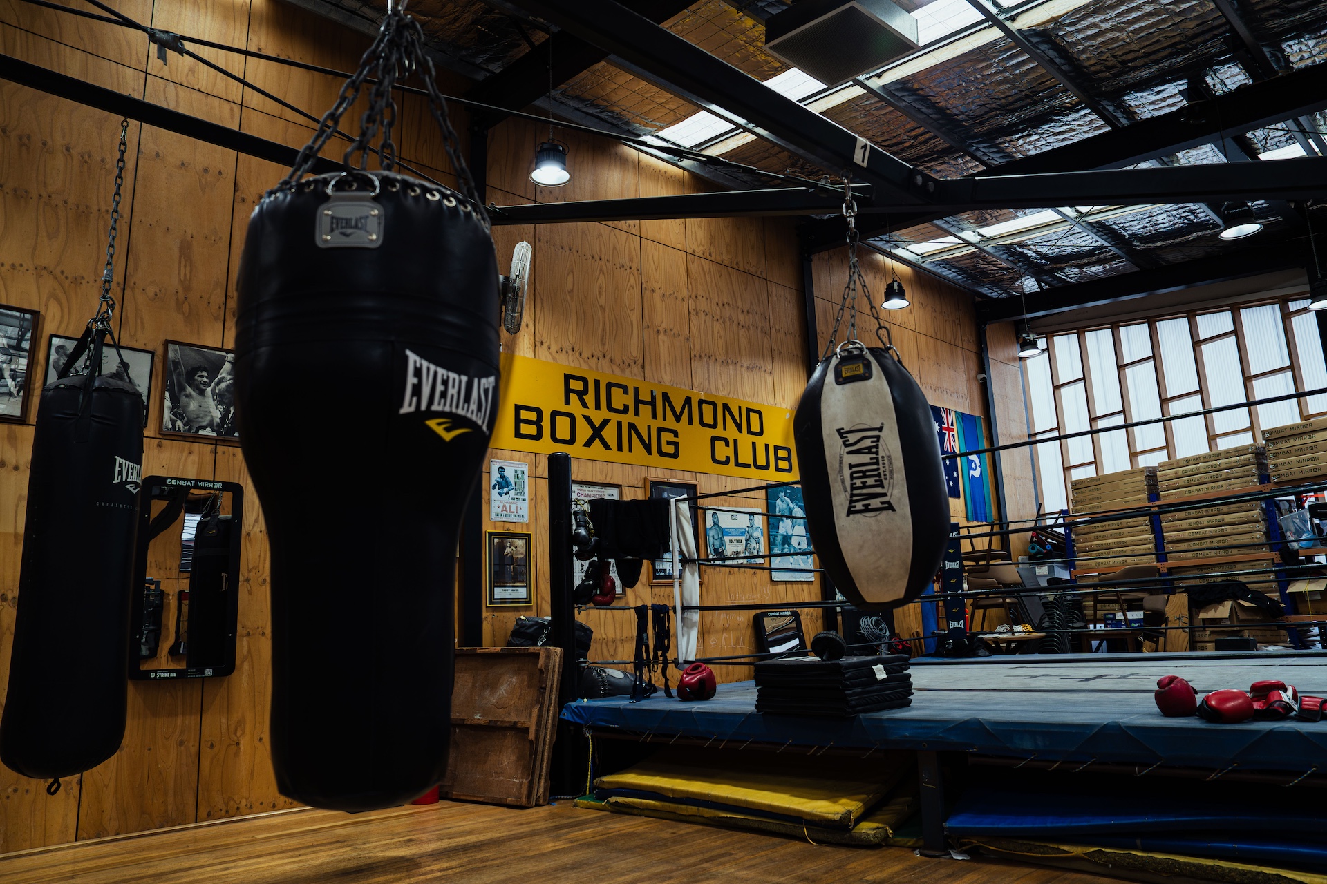 Heavy bags hanging beside the ring under the club sign